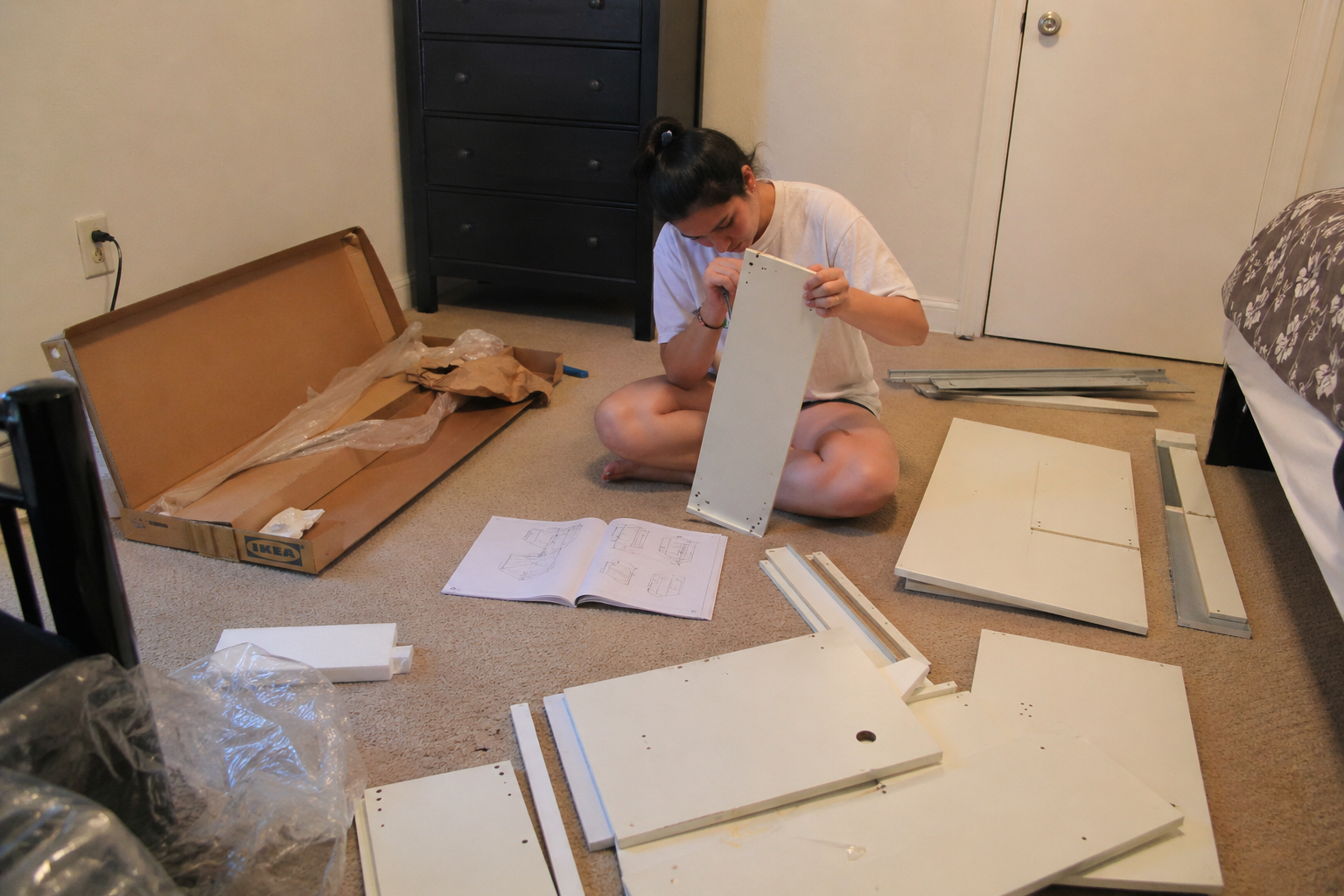 Person assembling IKEA furniture on the floor — parts spread around
